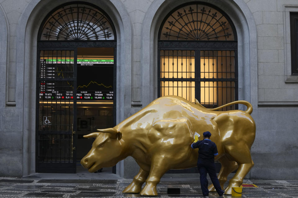 A worker cleans off a protest sign that read "hungry" in Portuguese, placed by activists on the Golden Bull, a replica of Wall street Charging Bull symbolizing the financial market outside the Brazilian B3 Stock Exchange in Sao Paulo, Brazil, Wednesday, Nov. 17, 2021. (AP Photo/Andre Penner)