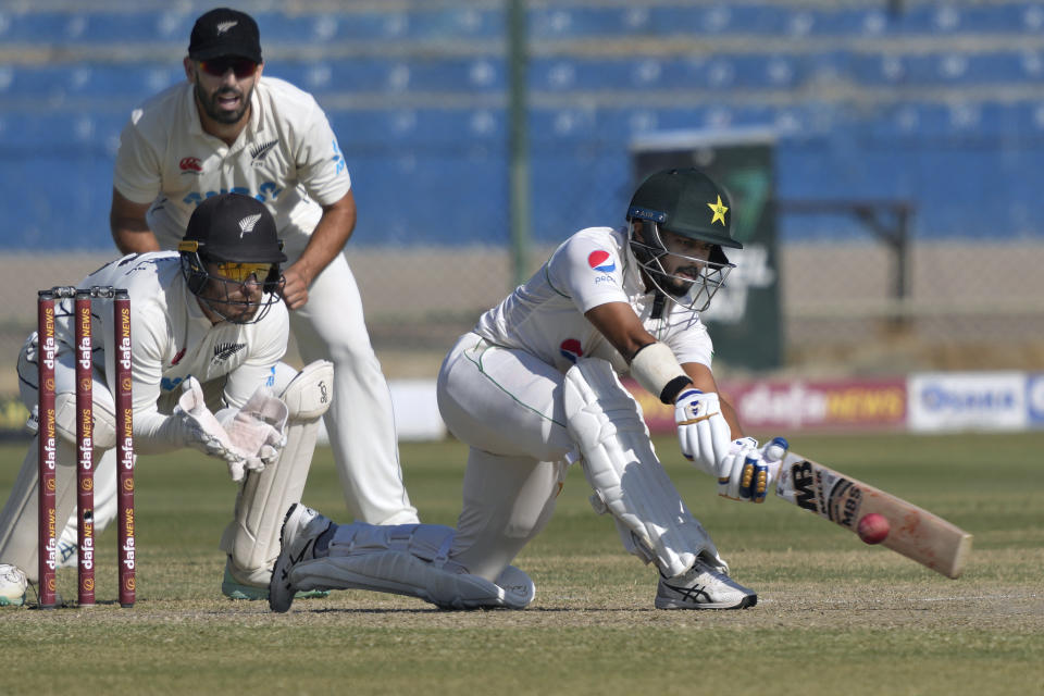 Pakistan's Saud Shakeel, right, plays a shot as New Zealand's Tom Blundell, left front, and Daryl Mitchell watch during the third day of the second test cricket match between Pakistan and New Zealand, in Karachi, Pakistan, Wednesday, Jan. 4, 2023. (AP Photo/Fareed Khan)