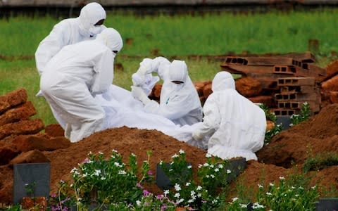 Paramedics wear protective suits as they bury a victim of the Nipah virus in Kerala, India  - Credit: K. Shijith/AP