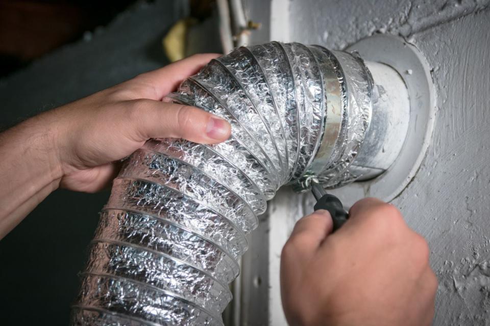 A close up of hands using a tool to fix as silver tube.