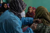 Kashmiri village girls watch as Ameena Banoo receives the vaccine for COVID-19 from Masrat Farid, a healthcare worker, during a COVID-19 vaccination drive in Gagangeer, northeast of Srinagar, Indian controlled Kashmir, Jan. 12, 2022. (AP Photo/Dar Yasin)