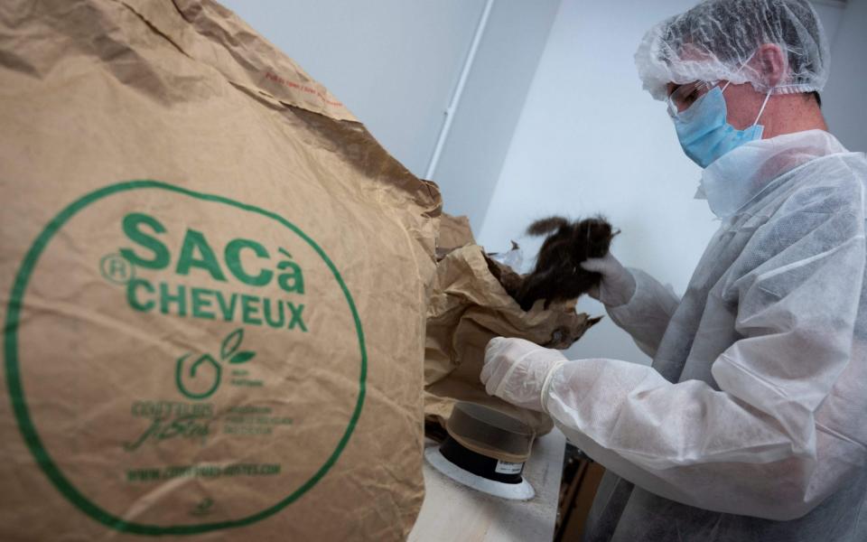 A worker fills paper bags with hairs received from hairdressers in France and used to make hydrocarburant absorbent draft snake -  CHRISTOPHE SIMON/AFP