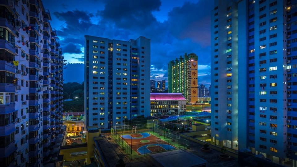 Night picture of HDB flats with a basketball court in the middle