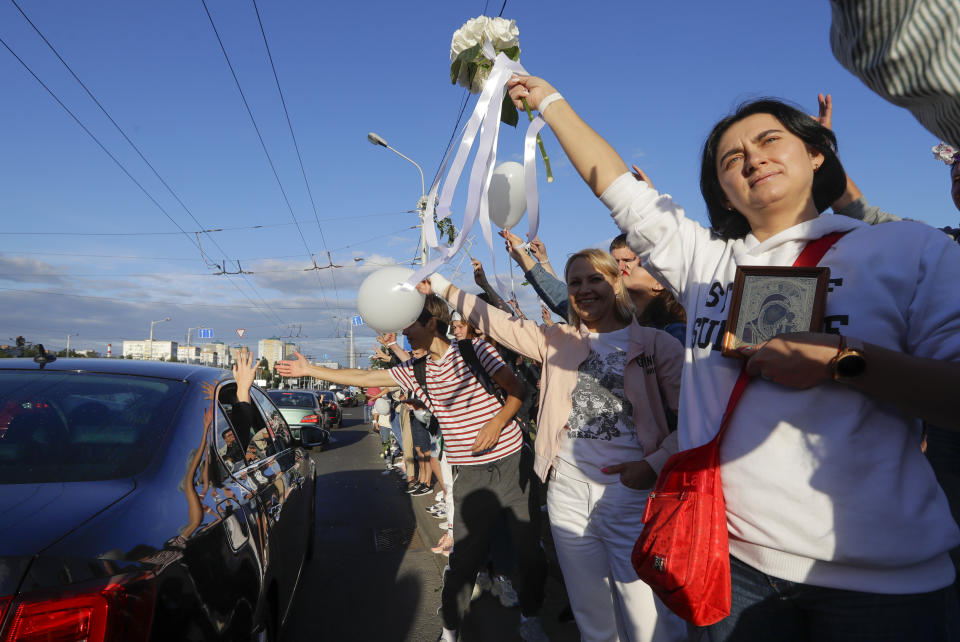 People greet each other waving flowers and white balloons as they gather in a street to protest against the results of the country's presidential election in Minsk, Belarus, Thursday, Aug. 13, 2020. Crowds of protesters in Belarus swarmed the streets and thousands of workers rallied outside industrial plants to denounce a police crackdown on demonstrations over a disputed election that extended the 26-year rule of authoritarian President Alexander Lukashenko. (AP Photo/Sergei Grits)