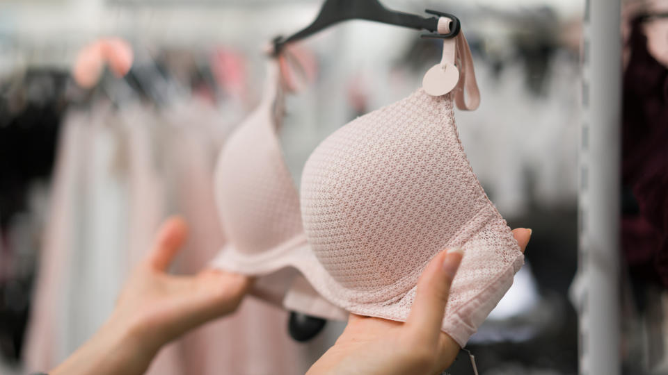 A person holds a bra hanging on a hanger