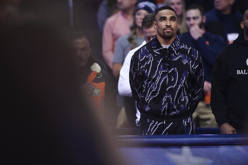 Philadelphia Eagles quarterback Jalen Hurts stands courtside for the national anthem before an NCAA college basketball game between Syracuse and Virginia in Syracuse, N.Y., Monday, Jan. 30, 2023. (AP Photo/Adrian Kraus)