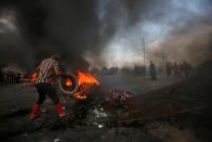 A protester places a tire in the fire during ongoing anti-government protests in Basra