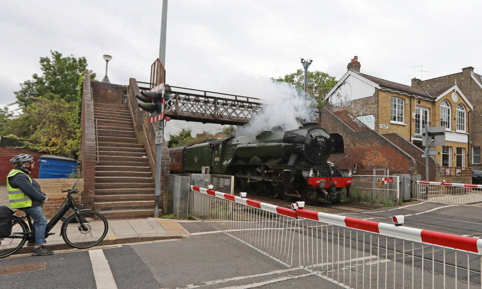 <p>The National Railway Museum's Flying Scotsman passes over a level crossing in Chiswick, west London, on its first main line trip with passengers since 2019 as part of The Steam Dreams Rail Company's series of summer trains from London Victoria Station. Picture date: Thursday May 20, 2021.</p>
