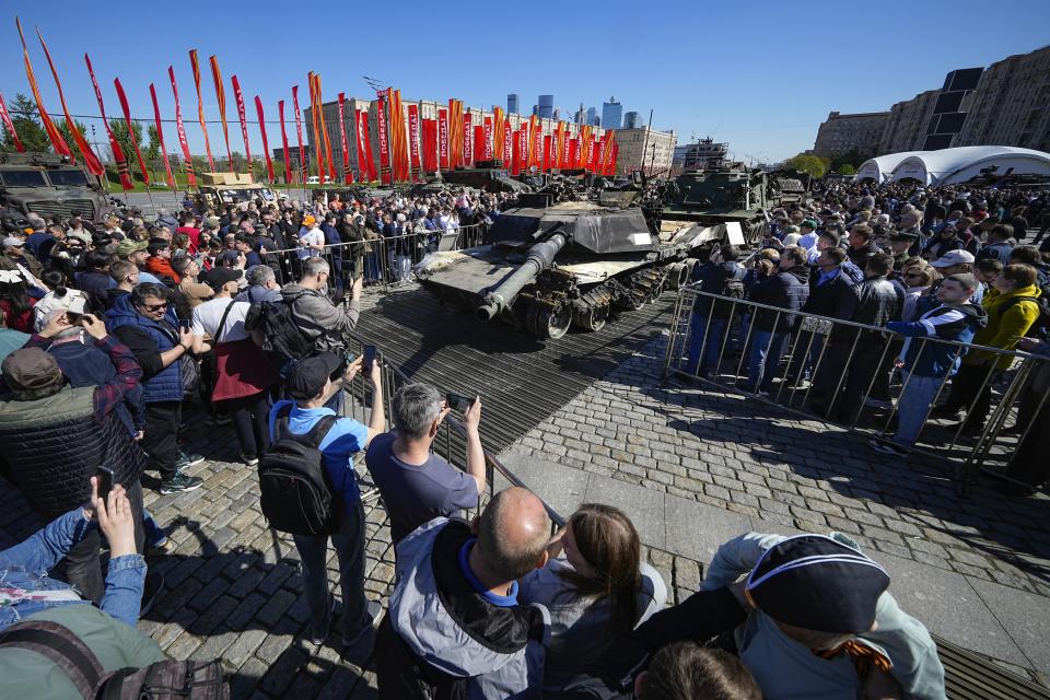 Visitors look at and take photos of a U.S. made M1A1 Abrams tank, foreground, hit and captured by Russian troops during the fighting in Ukraine which is seen on display in Moscow, on Wednesday, May 1, 2024. An exhibition of military equipment captured from Kyiv forces during the fighting in Ukraine has opened in the Russian capital. (AP Photo/Alexander Zemlianichenko)