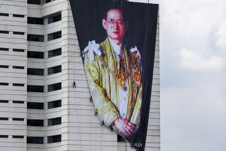 Workers install a portrait of Thailand's late King Bhumibol Adulyadej at a building in Bangkok, Thailand, October 21, 2016. REUTERS/Athit Perawongmetha
