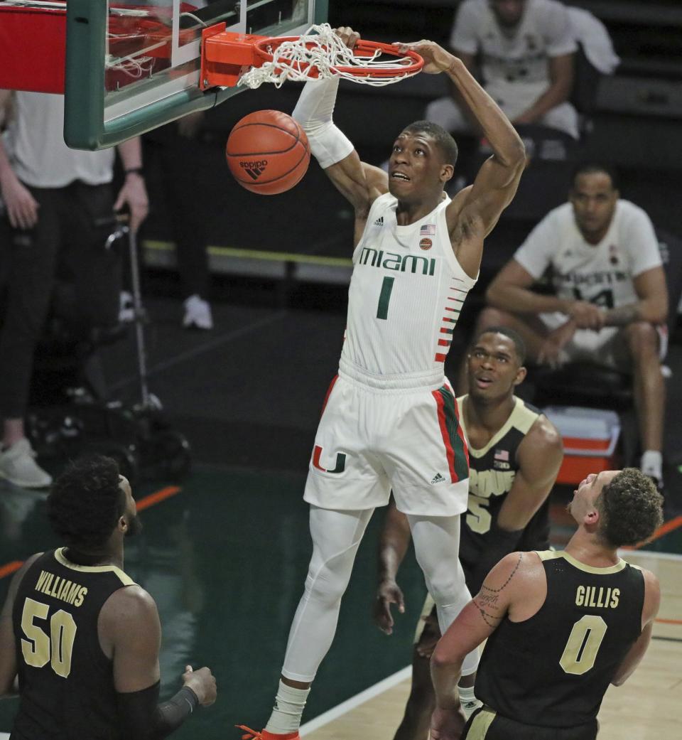 Miami forward Anthony Walker (1) dunks over Purdue defenders during the second half of an NCAA college basketball game Tuesday, Dec. 8, 2020, in Coral Gables, Fla. (Al Diaz/Miami Herald via AP)
