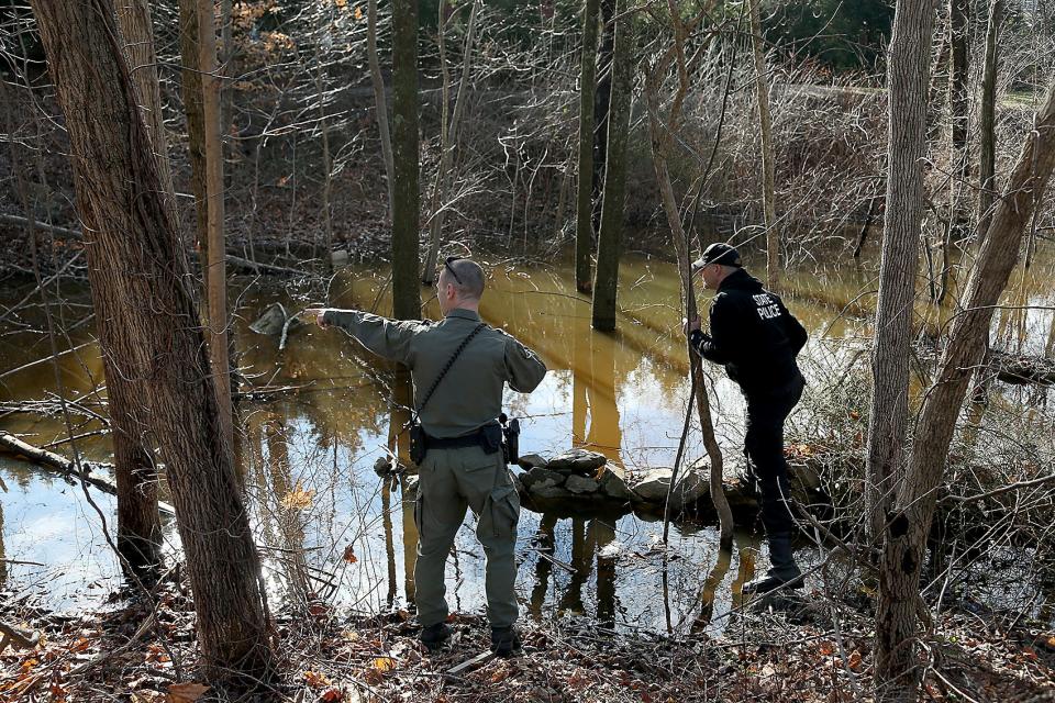 An Massachusetts environmental police officer points out something to a state trooper during their search for Ana Walshe across the street from her home on Rt. 3A in Cohasset on Saturday, Jan. 7, 2023. 