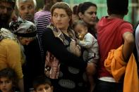 Syrian refugees and migrants line up with children at a registration camp in Presevo, upon their arrival in Serbia on August 30, 2015