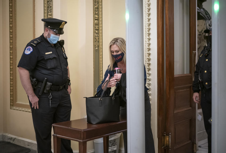 Rep. Marjorie Taylor Greene, R-Ga., an ally of President Donald Trump, passes through a metal detector before entering the House chamber, a new security measure put into place after a mob stormed the Capitol, in Washington, Tuesday, Jan. 12, 2021. The House is trying to push the vice president and Cabinet to act even more quickly to remove President Donald Trump from office. Democrats are set to pass a resolution calling on Vice President Mike Pence to invoke constitutional authority under the 25th Amendment to oust Trump. (AP Photo/J. Scott Applewhite)