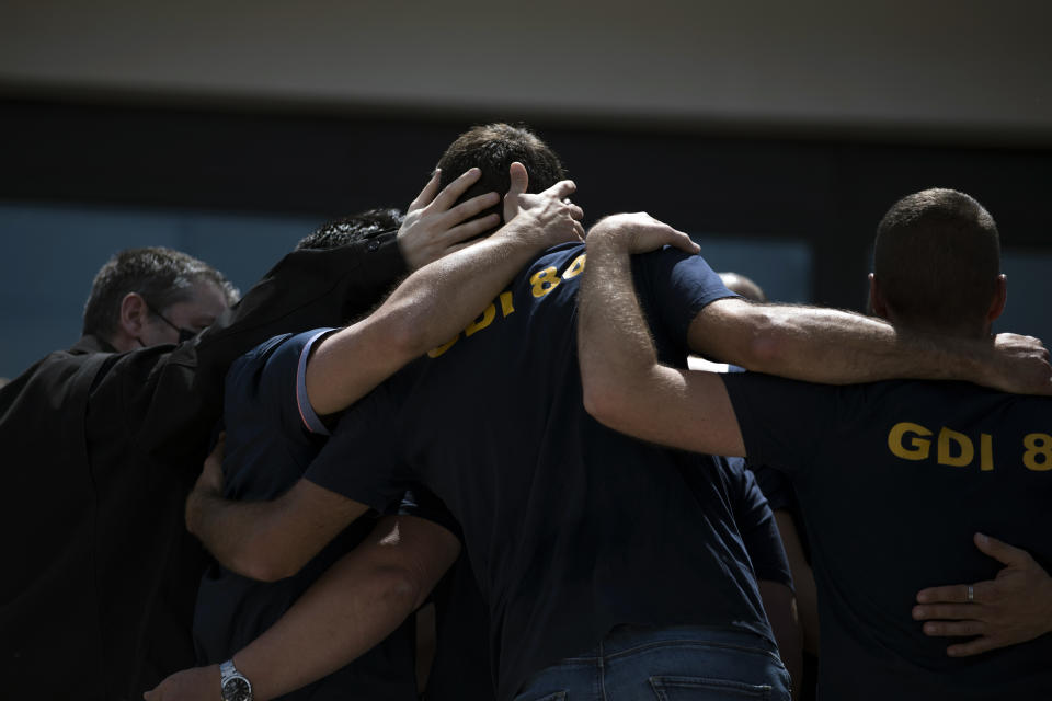 Police officers console each other during a ceremony to commemorate a slain colleague at a police station in Avignon, southern France, Sunday, May 9, 2021. Police officers and civilians gathered to commemorate the death of a police officer who was killed Wednesday at a known drug-dealing site in the southern France city of Avignon. (AP Photo/Daniel Cole)