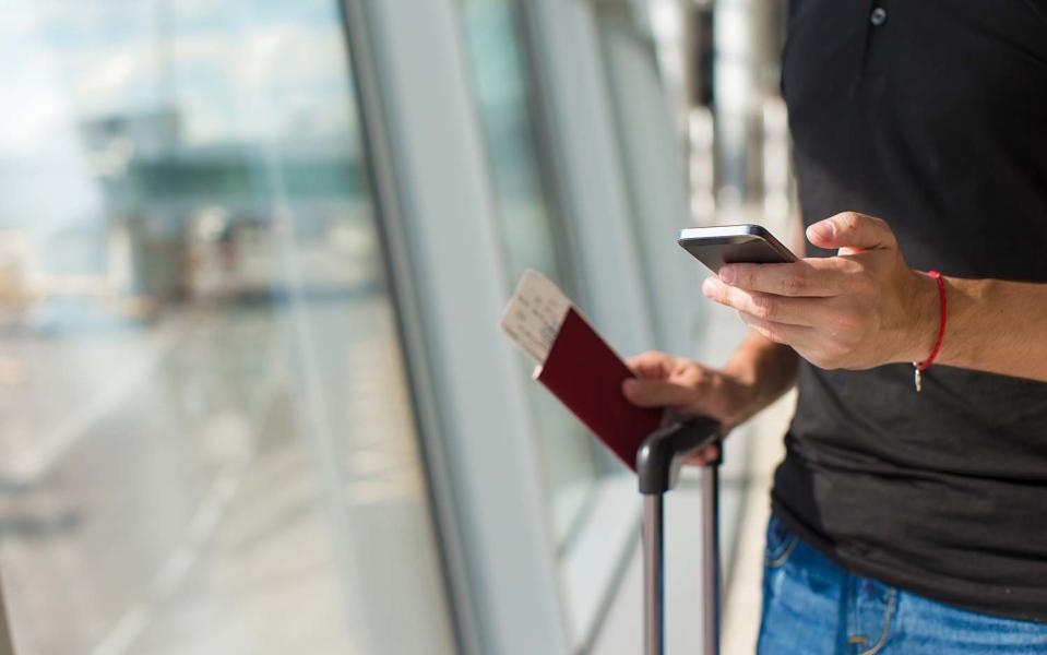 Man at airport terminal holding passport, ticket and phone