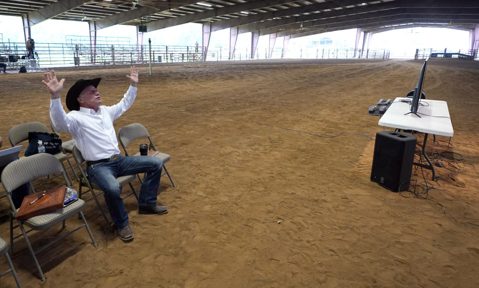 Lone Start Cowboy Church Lead Pastor Randy Weaver raises his hands in prayer during a livestream of their Easter service Sunday, April 12, 2020, in Montgomery, Texas. The service was held in the church's empty dirt arena where normally thousands would have attended but could not due to social distancing guidelines during the coronavirus outbreak. (AP Photo/David J. Phillip)