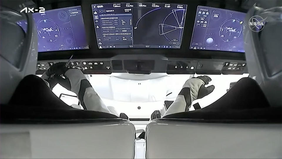 An over-the-shoulder view of Ax-2 commander Peggy Whitson, left, and co-pilot John Shoffner monitor touchscreen displays in their SpaceX Crew Dragon capsule during final approach to the International Space Station. / Credit: SpaceX