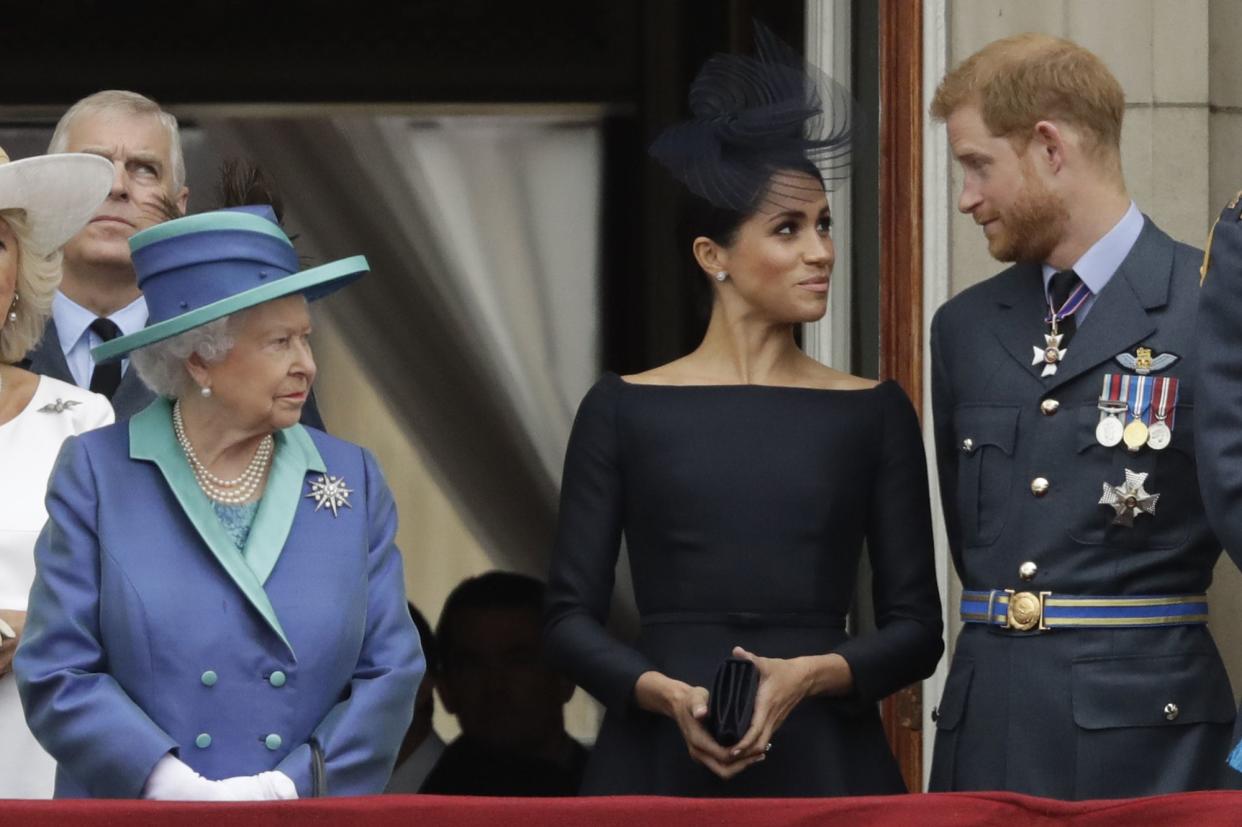 In this Tuesday, July 10, 2018 file photo Britain's Queen Elizabeth II, Meghan the Duchess of Sussex and Prince Harry stand on a balcony to watch a flypast of Royal Air Force aircraft pass over Buckingham Palace in London. 