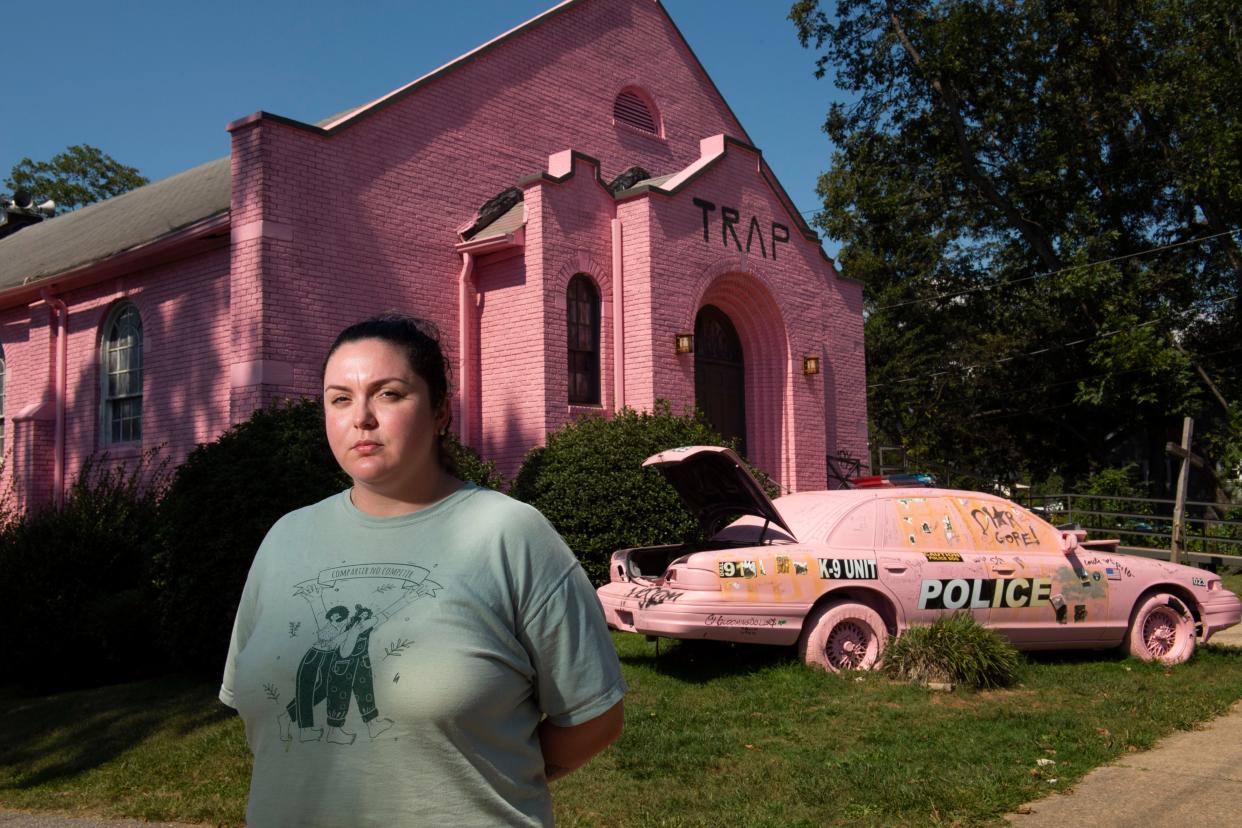 Dayna Lee, owner of Comal 864, poses for a portrait in front of the pink trap church owned by Rob Rallis, on Thursday, September 22, 2022. Lee, as a business owner in the neighborhood, is upset by what Rallis has done to the former Bible Way Full Gospel Missionary Baptist Church and the possibility of it becoming expensive apartments. 