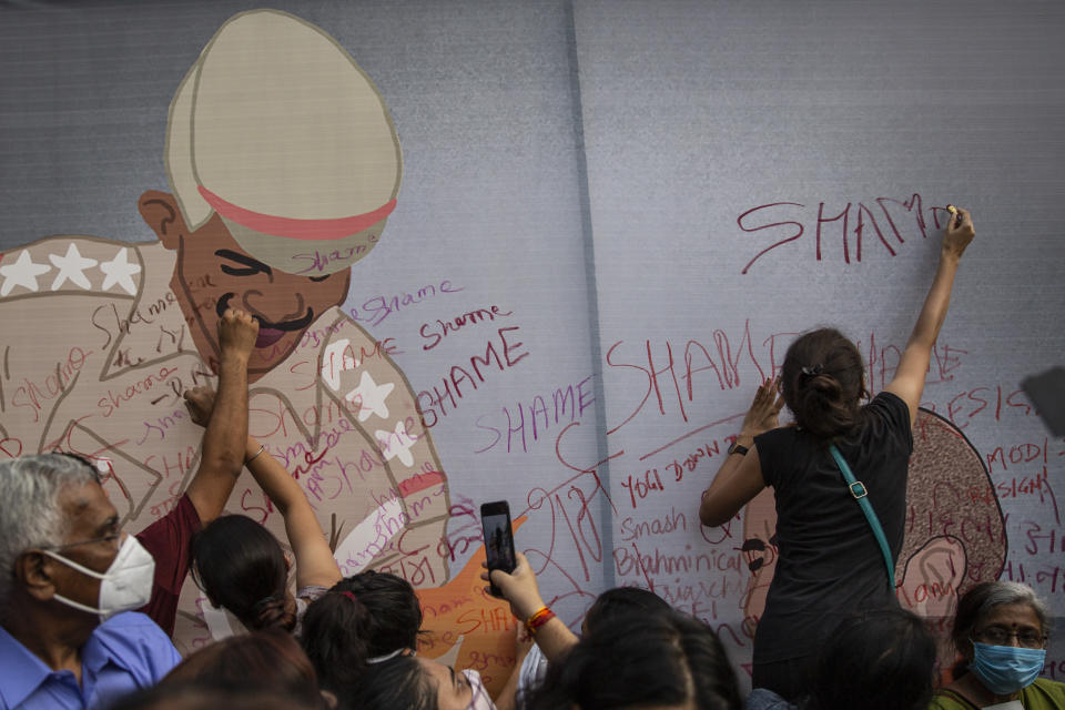 Activists cover a caricature of a policeman with the word "Shame" during a protest against the gang rape and killing of a woman in India's northern state of Uttar Pradesh, in New Delhi, India, Friday, Oct. 2, 2020. Hundreds of protesters on Friday demanded the dismissal of a Hindu nationalist government in a northern Indian state where a 19-year-old woman from India’s lowest caste was allegedly gang raped and brutally attacked last month and later died in a hospital. The woman was cremated early Wednesday, with the family alleging that police did not allow them to perform her final rites. Videos on social media show the family weeping as police insisted on cremating the body without allowing them to take it home. (AP Photo/Altaf Qadri)
