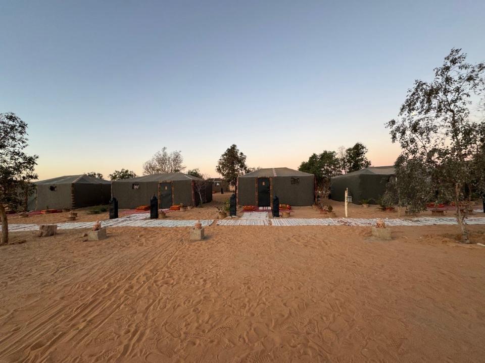 Row of small glamping tents in Sahara Desert surrounded by sand 