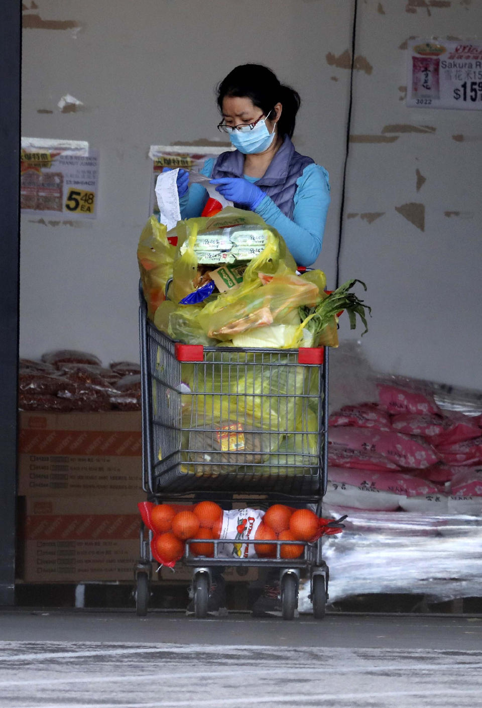 Wearing a mask amid concerns of the spread of COVID-19, a woman checks her receipt after shopping for groceries in Richardson, Texas, Wednesday, April 1, 2020. (AP Photo/LM Otero)