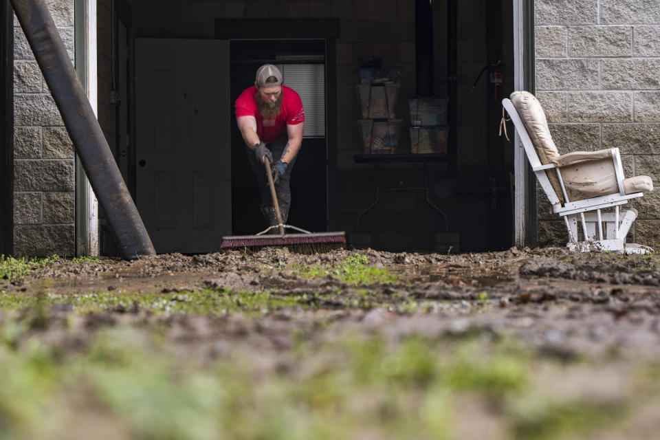 Brandon Ammon sweeps mud that washed through his garage after the San Lorenzo River overflowed in the Felton Grove neighborhood of Felton, Calif., Tuesday, Jan. 10, 2023. (AP Photo/Nic Coury)