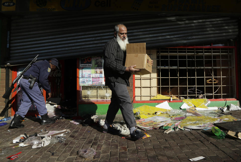 A business owner carries goods out of his damaged shop caused by looters in Germiston, east of Johannesburg, South Africa, Tuesday, Sept. 3, 2019. Police had earlier fired rubber bullets as they struggled to stop looters who targeted businesses as unrest broke out in several spots in and around the city. (AP Photo/Themba Hadebe)