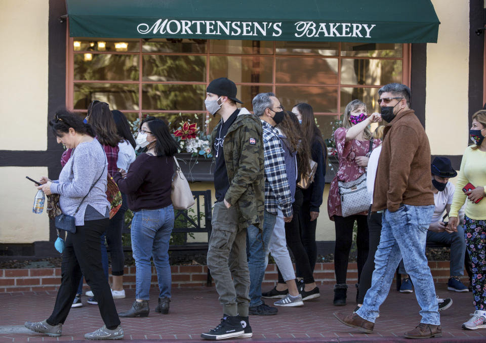 Groups of people, some wearing masks, take over the sidewalks downtown in Solvang, California, on Nov. 28, 2020. It was almost two weeks ago that the popular California tourist town of Solvang made headlines when it said it wouldn't enforce Gov. Gavin Newsom's tough new stay-at-home orders. But that was a week before a new City Council took over and told everyone to obey the rules to save lives. (George Rose/Santa Ynez Valley Star via AP)