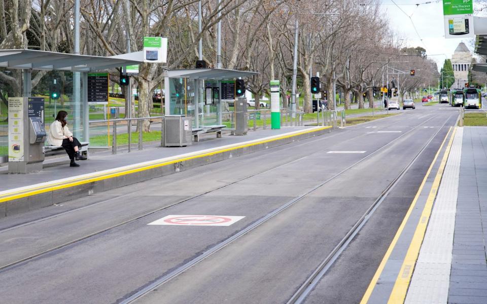 A lone passenger sits at a tram stop on a mostly-empty city centre street on the first day of a lockdown as the state of Victoria looks to curb the spread of a coronavirus disease (COVID-19) outbreak in Melbourne, Australia, July 16, 2021. REUTERS/Sandra Sanders/File Photo - Reuters