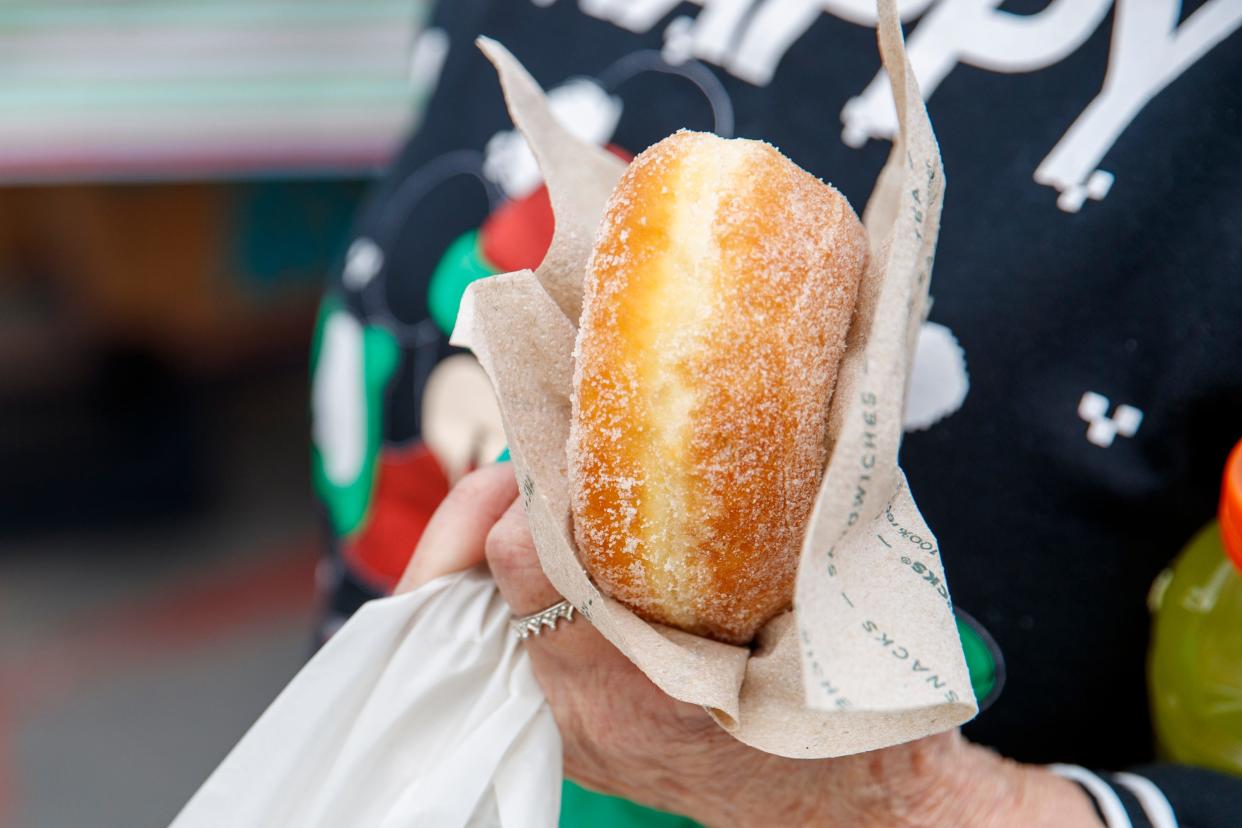 A woman holds a donut during a gift and hot meal giveaway at the Cathedral Palms Senior Housing Community in Cathedral City, Calif., on December 23, 2021.