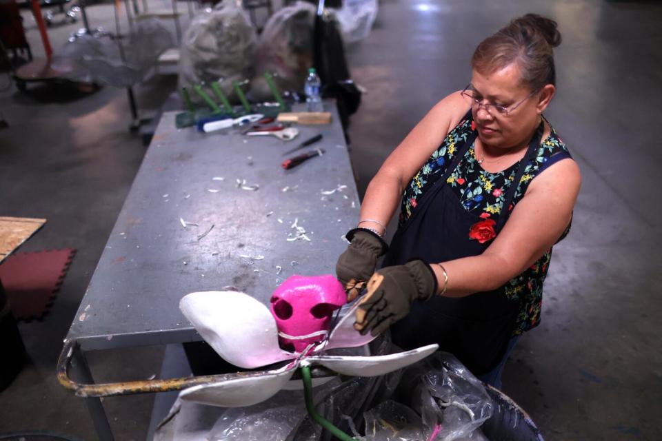 Maricela Arambala cuts the edges of a piece for a float at Fiesta Rose