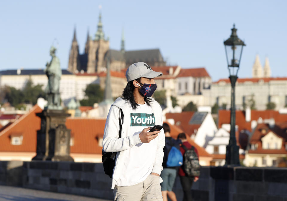 A young man wearing a face mask walks across the medieval Charles Bridge in Prague, Czech Republic, Friday, Sept. 18, 2020. The Czech Republic has been been facing the second wave of infections. The number of new confirmed coronavirus infections has been setting new records almost on a daily basis, currently surpassing 3,000 cases in one day for the first time. (AP Photo/Petr David Josek)