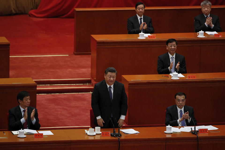 Party officials applaud as Chinese President Xi Jinping, standing, delivers his speech at the commemorating conference on the 70th anniversary of the Chinese army entering North Korea to resist the U.S. army, at the Great Hall fo the People in Beijing, Friday, Oct. 23, 2020. (AP Photo/Andy Wong)