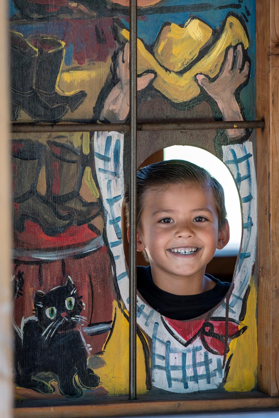 Jaxxon Tjaden, 5, of Stockton peeks out from one of the cutouts at the Pixie Woods Jail during the Christmas in July at Pixie Woods on July 23.