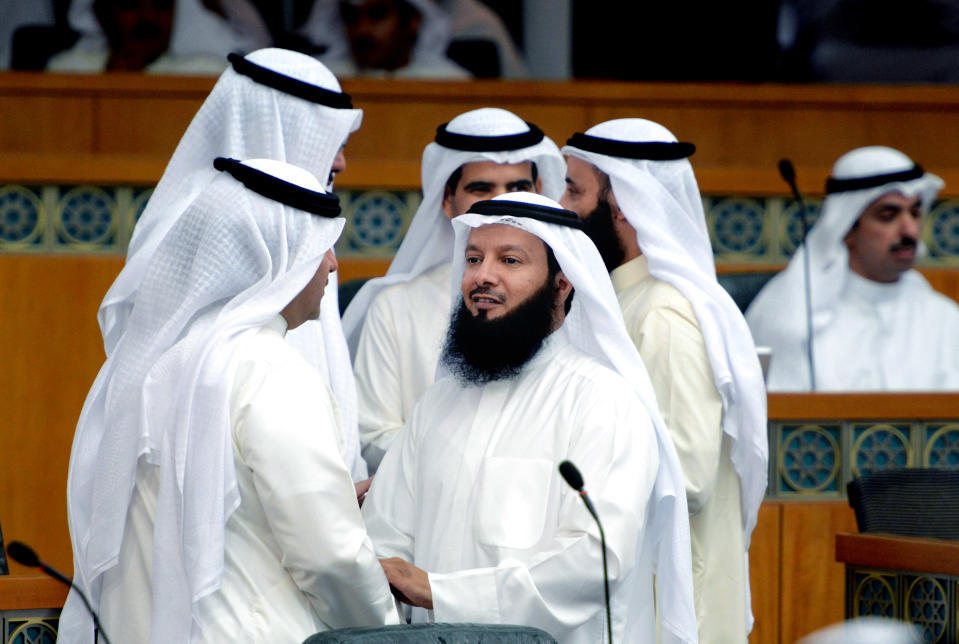 In this Wednesday, Sept. 4, 2013 photo, Kuwaiti Islamist AP Ahmed Al Azmi, center, speaks with lawmakers during a National Assembly session in Kuwait. One of the most traditional pleasures of the Middle East _ leisurely puffing on a water pipe filled with aromatic tobacco _ has become ensnared in another of the region's familiar backdrops: Islamic conservatives decrying what they see as liberal decadence. (AP Photo/Gustavo Ferrari)