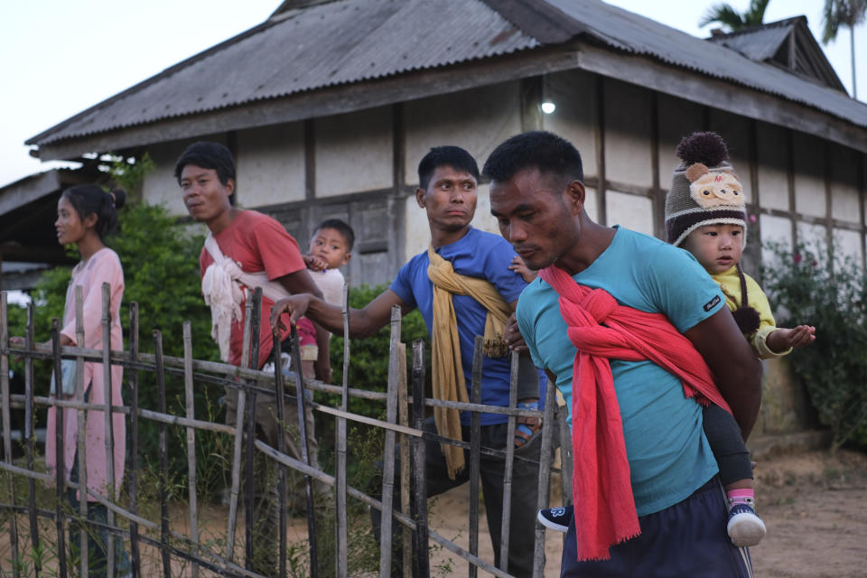 Villagers carry children on their backs and stand by a village square in Oting, in the northeastern Indian state of Nagaland, Wednesday, Dec. 15, 2021. High up in the hills along India's border with Myanmar, Oting village is in mourning after more than a dozen people were killed by Indian army soldiers. (AP Photo/Yirmiyan Arthur)