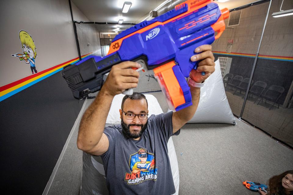 Luis Lopez holds up a dart gun at Dart World Gaming Arena downtown in Lakeland Fl. Friday January 28 ,  2022. Dart Arena to offer Nerf gun battles for families and parties. The arena is In a historic building formerly RP Funding offices. Loft is above the Dart World. ERNST PETERS/ THE LEDGER