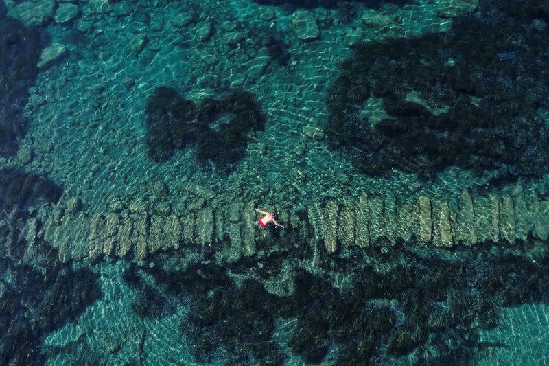 Un visitante observa las ruinas mientras nada en el parque arqueológico submarino del antiguo puerto de Amatunte, en Limasol, Chipre