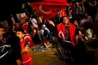 An old woman in her wheel chair waves a Turkish national flag as she gathered with others in solidarity outside Turkish President Tayyip Erdogan's palace night after night since the July 15 coup attempt in Ankara, Turkey, July 27, 2016. REUTERS/Umit Bektas