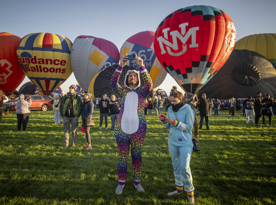 Walter Myal, left and his girlfriend Chelsea Peterson witness the start of the Albuquerque International Balloon Fiesta Saturday, Oct. 7, 2023 in Albuquerque, N.M. (AP Photo/Roberto E. Rosales)