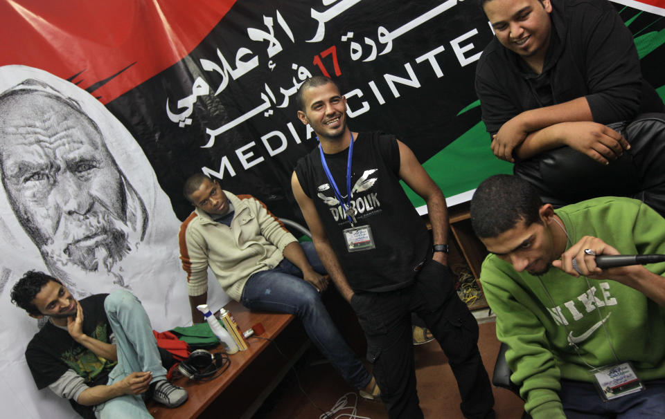 In this photo taken Tuesday, April 19, 2011, Youssef al-Briki, 24, a.k.a. SWAT, center, Mohammed al-Yemeni, 24, a.k.a. Migo, far left, and other members of the Revolution Beat rap group hang out next to a banner of Libya's legendary anti-Italian fighter Omar al-Mukhtar, in their makeshift studio in a room of the media center in Benghazi, Libya.In the five decades since hip-hop emerged out of New York City, it has spread around the country and the world. And at each step there's been change and adaptation, as new, different voices came in and made it their own. Its foundations are steeped in the Black communities where it first made itself known but it's spread out until there’s no corner of the world that hasn’t been touched by it. (AP Photo/Ben Curtis, file)