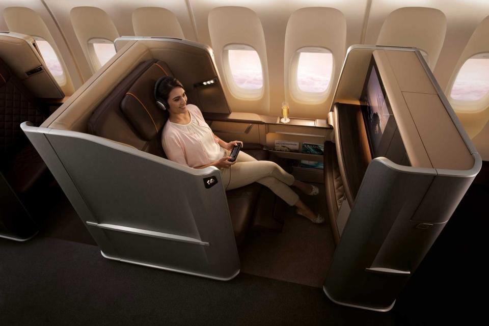 A woman sits in business class on a Singapore Airways plane