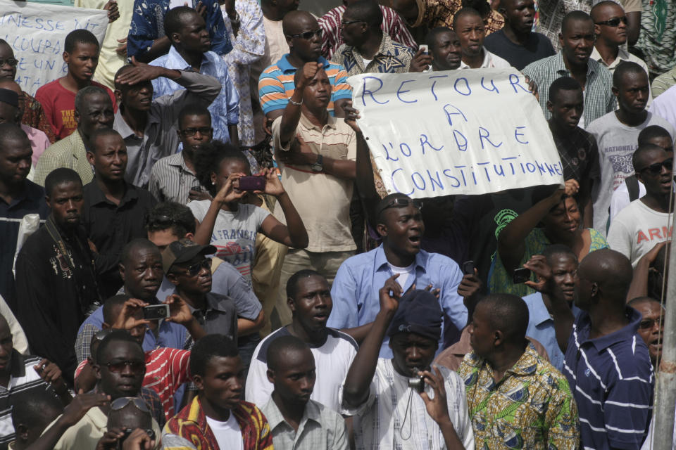 People gather in protest against the recent military coup, in Bamako, Mali, Monday, March 26, 2012, with one protester holding a sign reading 'Return to constitutional order'. About a thousand demonstrators protested Monday in Mali's capital to demand a return to constitutional order days after mutinous soldiers claimed power in a coup.(AP Photo/Harouna Traore)