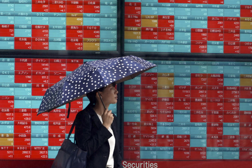 A woman walks past an electronic stock board showing Japan's Nikkei 225 index at a securities firm in Tokyo Friday, July 12, 2019. Shares in Asia are mostly higher after a turbulent day on Wall Street ended with the Dow Jones Industrial Average closing above 27,000 for the first time. (AP Photo/Eugene Hoshiko)