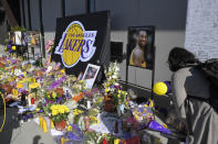 Fans look at a memorial to former Los Angeles Lakers player Kobe Bryant at the NBA basketball team's practice facility Wednesday, Jan. 29, 2020, in El Segundo, Calif. Bryant, his 13-year-old daughter, Gianna, and seven others died in a helicopter crash on Sunday, Jan. 26. (AP Photo/Mark J. Terrill)