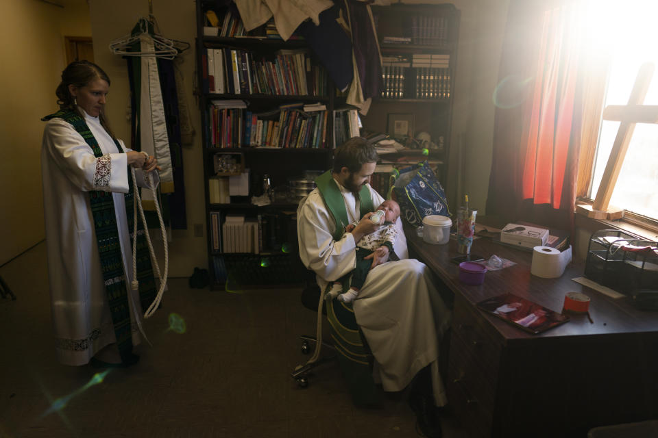 The Rev. Aaron Silco, center, who is a co-pastor of the Shishmaref Lutheran Church with his wife, Anna, left, feeds their two-month-old son, Aidan, while getting ready for a Sunday service in Shishmaref, Alaska, Sunday, Oct. 2, 2022. (AP Photo/Jae C. Hong)