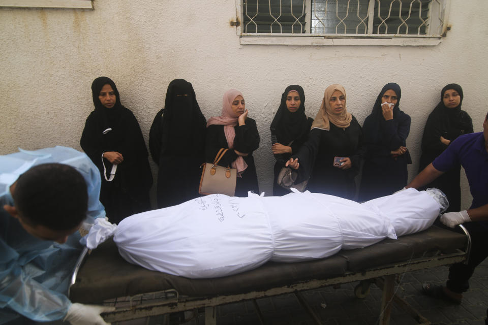 Palestinian women stand next to the body of a person killed in the Israeli bombing of the Gaza Strip in Rafah on Tuesday, Oct. 24, 2023. (AP Photo/Hatem Ali)