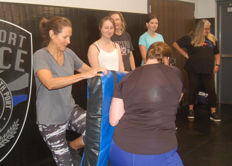 A self-defense class participant practices driving her knee with a kicking pad held by North Port police Sgt. Shannon Fortuno.